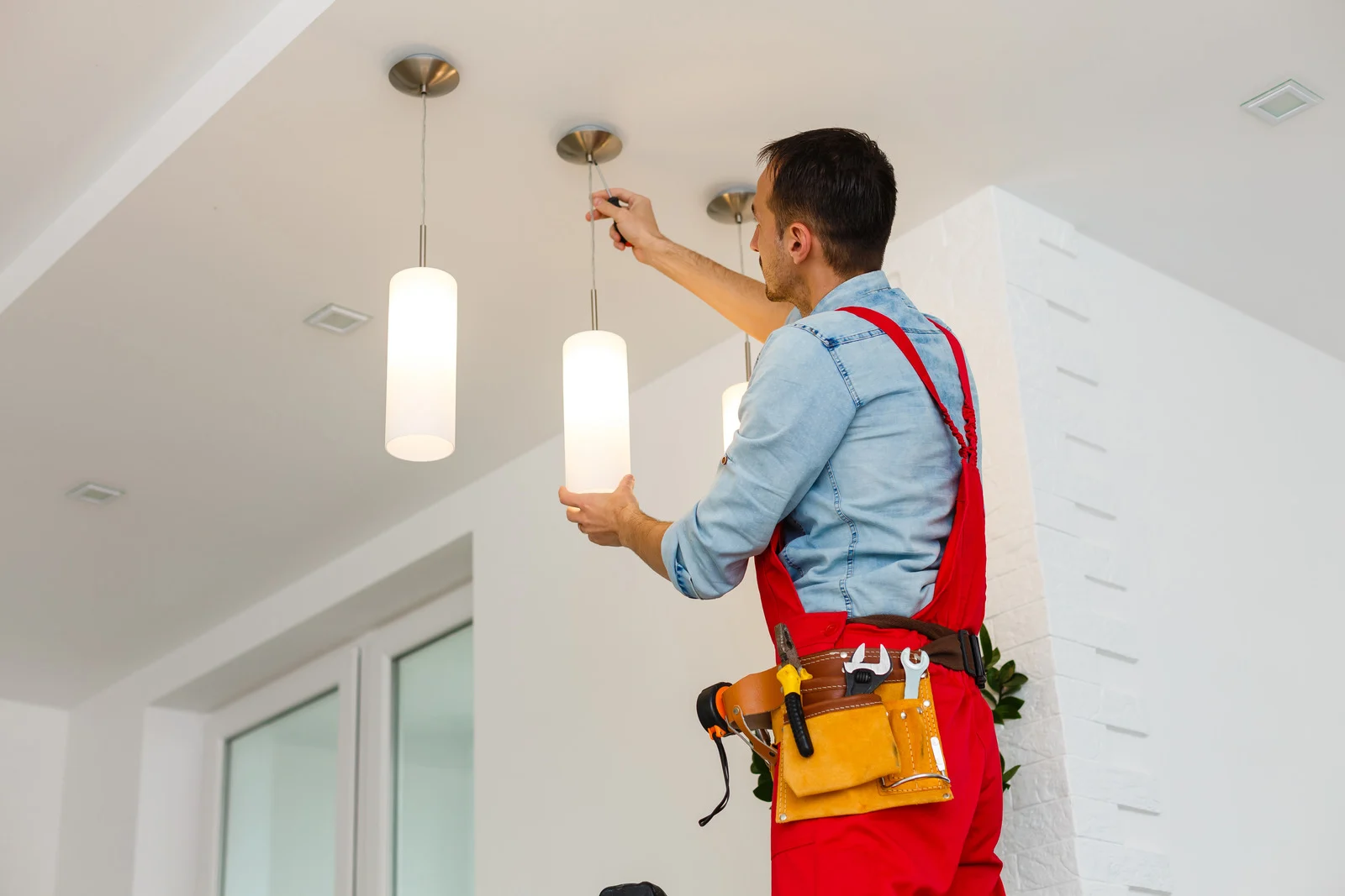 Electrician fitting a pendant light fixture during a lighting upgrade
